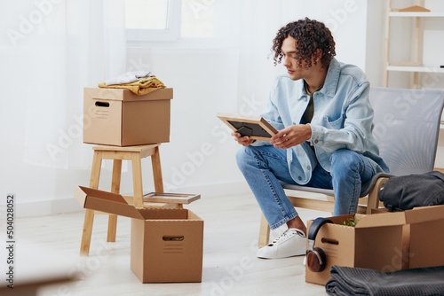 guy with curly hair cardboard boxes in the room unpacking Lifestyle