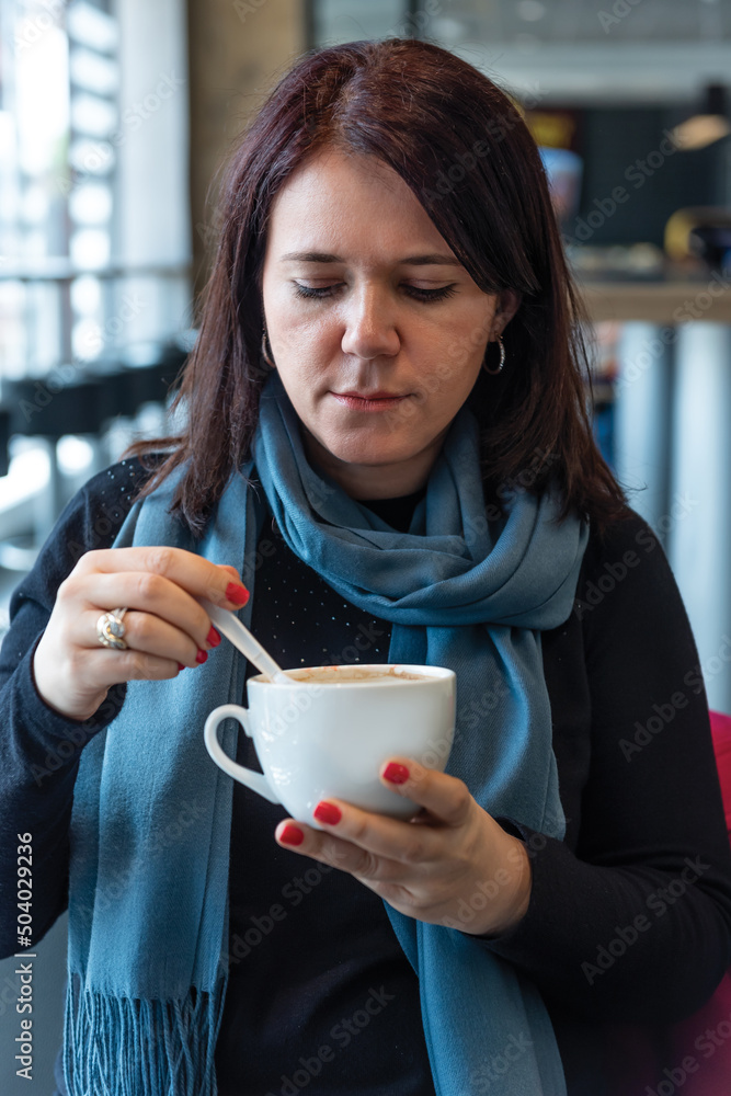 Thoughtful mature woman sitting in cafeteria holding coffee mug. Middle aged woman drinking tea while thinking. Relaxing and thinking while drinking coffee.