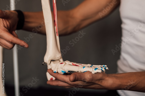 A man holds a skeleton leg in his hands and points a finger at it photo