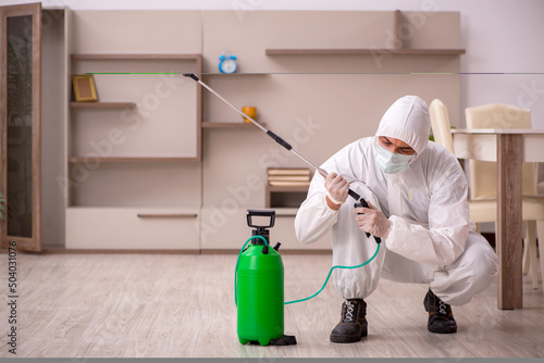 Young male contractor doing pest control at home