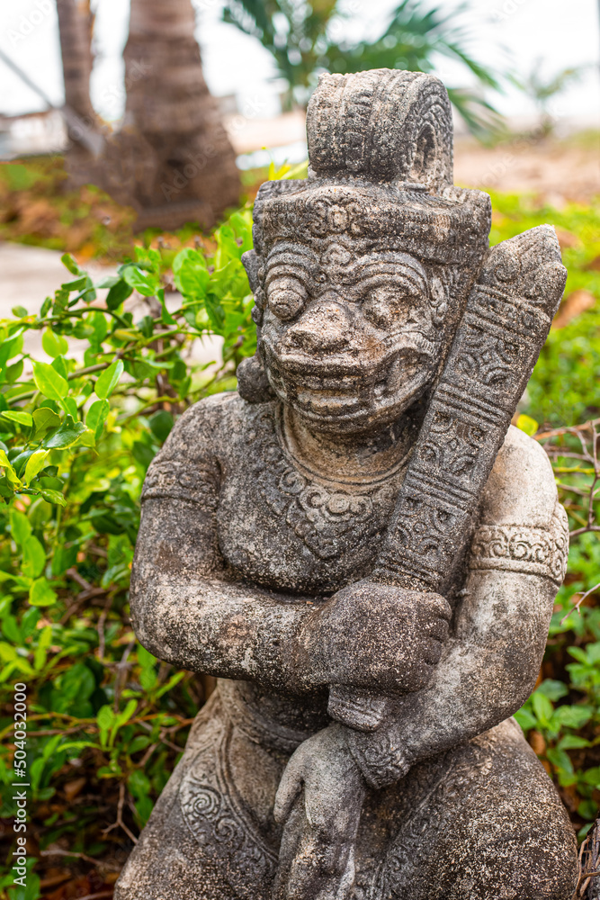 Asian statue of a creature with bulging eyes in a tropical park. Travel and tourism