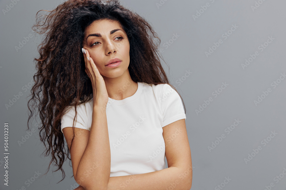 Tired latin afro-haired woman lady 20s 30s years old wearing white casual t-shirt standing put hand on head having headache looking aside isolated on gray color background studio portrait Copy space Tired latin afro-haired woman lady 20s 30s years old wearing white casual t-shirt standing put hand on head having headache looking aside isolated on gray color background studio portrait Copy space