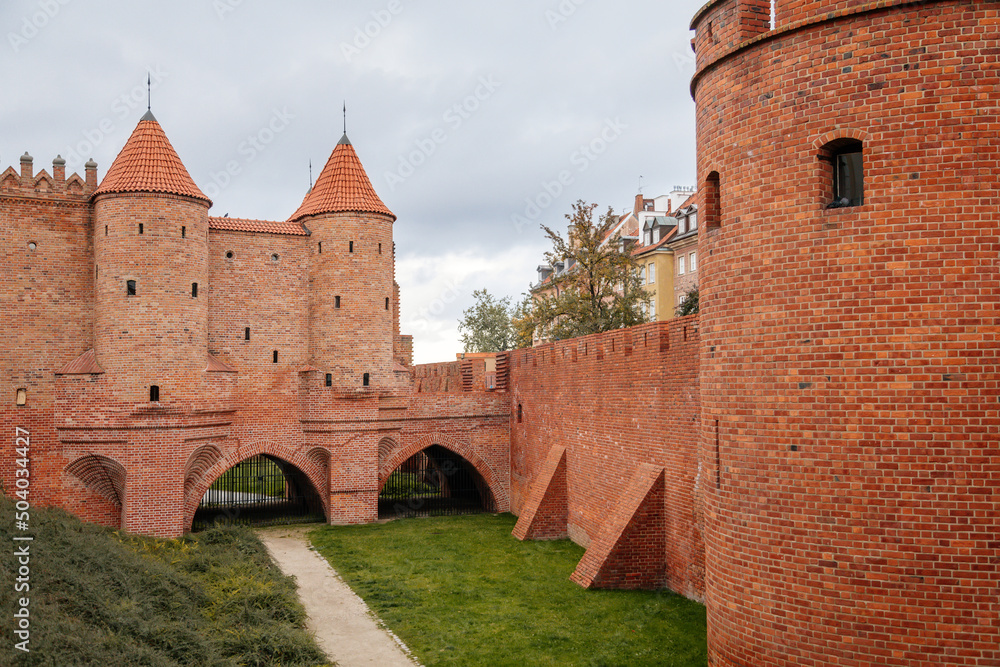 Warsaw, Poland, 13 October 2021: Barbican complex network of historic fortifications between Old and New Town, red brick fort wall with towers, major tourist attraction at sunny autumn day, city gate