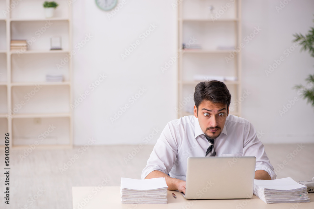 Obraz premium Young male employee unhappy with excessive work in the office