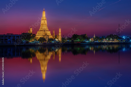 View of the Wat Arun temple at sunset with reflections in the water