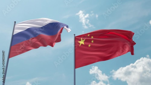 Flag of Russia and China on the flagpole flutters quickly with a strong wind in the blue sky