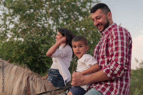 The family spends time with their children while riding horses together on a forest road. Selective focus 