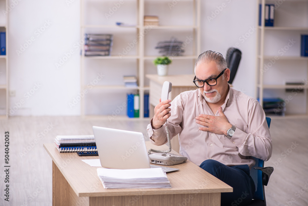 Old male employee working at workplace Old male employee working at workplace