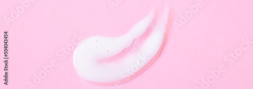 Close-up cream moisturiser smear smudge wavy texture on pink. background with copy space horizontal banner format. Skin care beauty product
