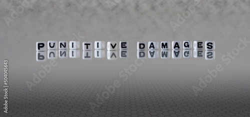 punitive damages word or concept represented by black and white letter cubes on a grey horizon background stretching to infinity photo