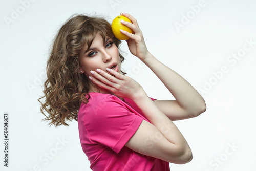 attractive girl holds a lemon in her hands. photo shoot in the studio on a white background © Vadzim