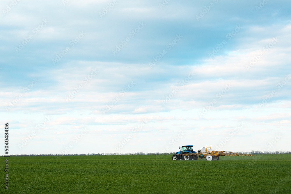Tractor spraying pesticide in field on spring day. Agricultural industry Tractor spraying pesticide in field on spring day. Agricultural industry