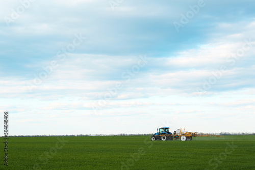 Tractor spraying pesticide in field on spring day. Agricultural industry