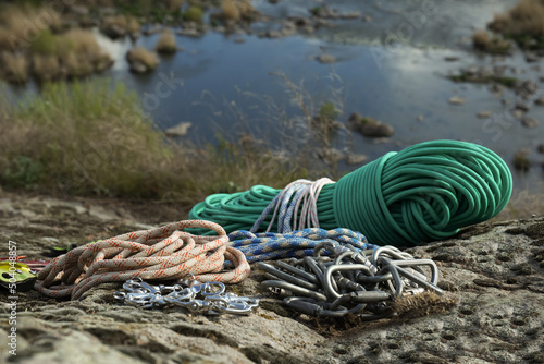 Different ropes and other climbing equipment on rock near river