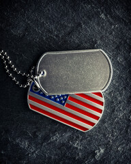 US military soldier's dog tags, rough and worn with blank space for text, and in the shape of the American flag. Memorial Day for Veterans Day concept.