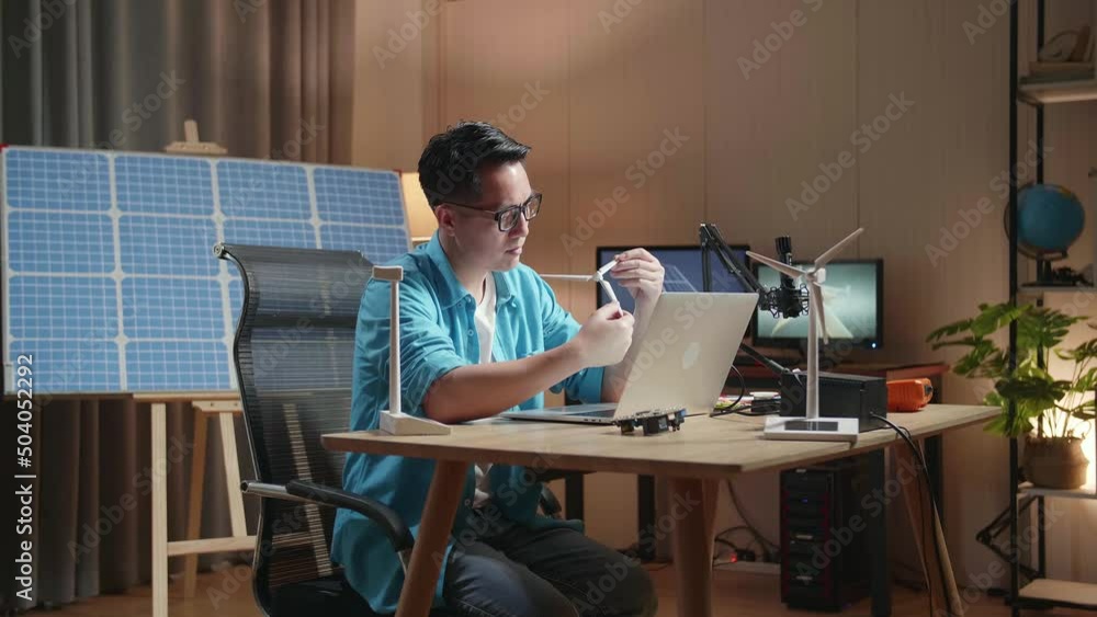 Asian Man Looks At Wind Turbine While Working With Laptop Next To The Solar Cell At The Office
Asian Man Looks At Wind Turbine While Working With Laptop Next To The Solar Cell At The Office