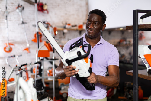 Ordinary man is buying new chainsaw in a tool store