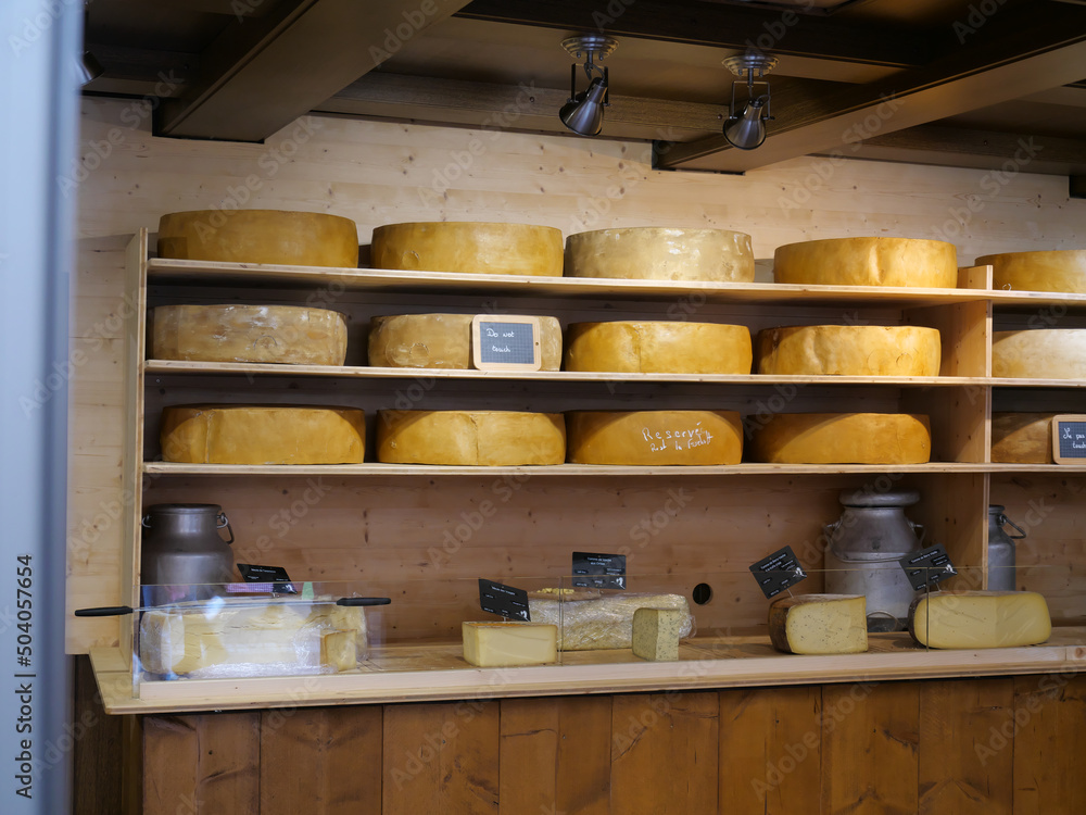 Große ganze und angeschnittene gelbe Käselaiber liegen in Regalen in einem Käseverkaufsladen im Elsass