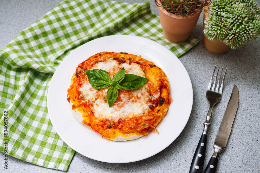 Homemade Margherita pizza with cheese, tomato sauce and basil leaf with crispy crust.