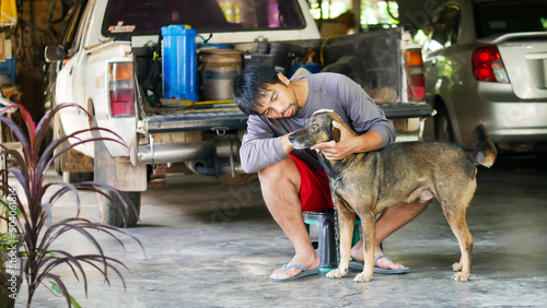 The concept of dogs and humans. An Asian man sits with a dog in his home. Date 12 May 2022 Thailand