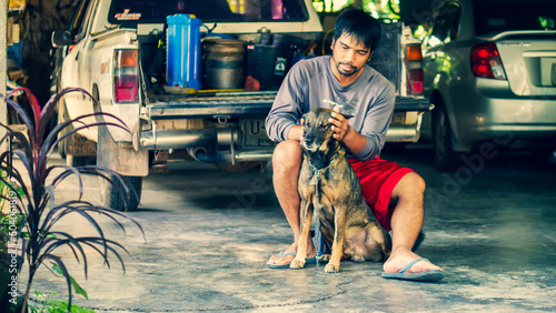 The concept of dogs and humans. An Asian man sits with a dog in his home. Date 12 May 2022 Thailand