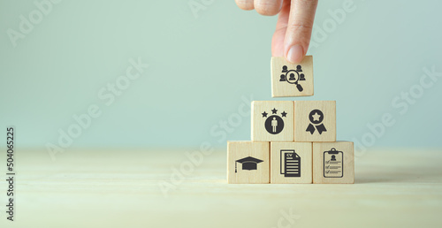 HRM and recriutement concept.  Job search, headhunting and recruitment process. Holding wooden cubes with icons of education, qualification, cv, resume, skills and experience on smart grey background.