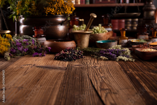 Natural medicine background. Assorted dry herbs in bowls and brass mortar on rustic wooden table.