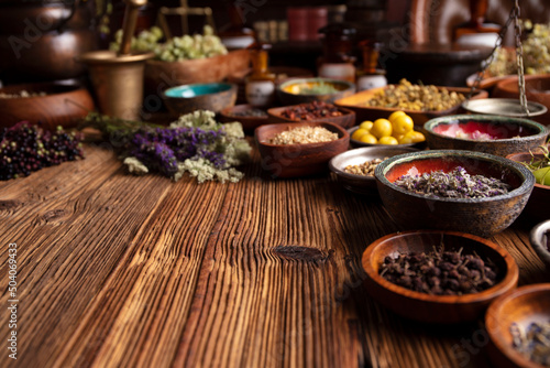 Natural medicine background. Assorted dry herbs in bowls and brass mortar on rustic wooden table.