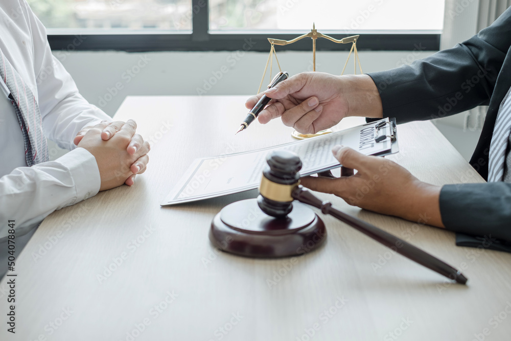 A man lawyer or a judge counseling clients about judicial justice and prosecution with scales, judges gavel, legal documents legal services concept A man lawyer or a judge counseling clients about judicial justice and prosecution with scales, judges gavel, legal documents legal services concept