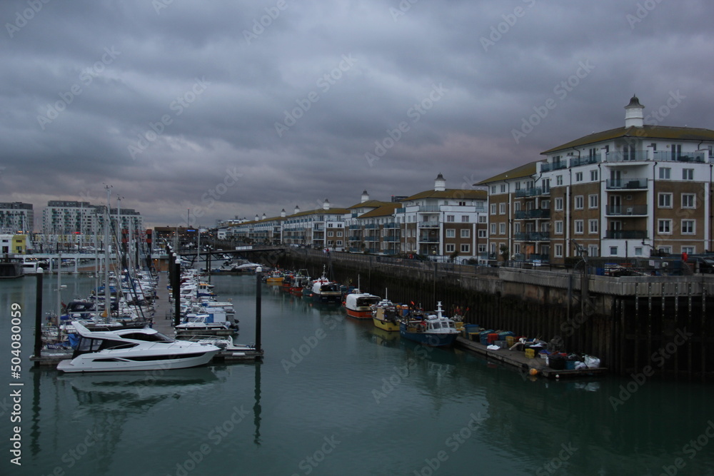 Brighton Marina during a cloudy sunset.  Moored ships on the water. 