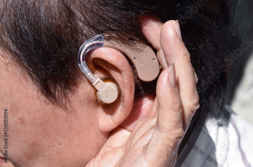 Electronic hearing aid device in the ear of Asian old man with total deafness. photo