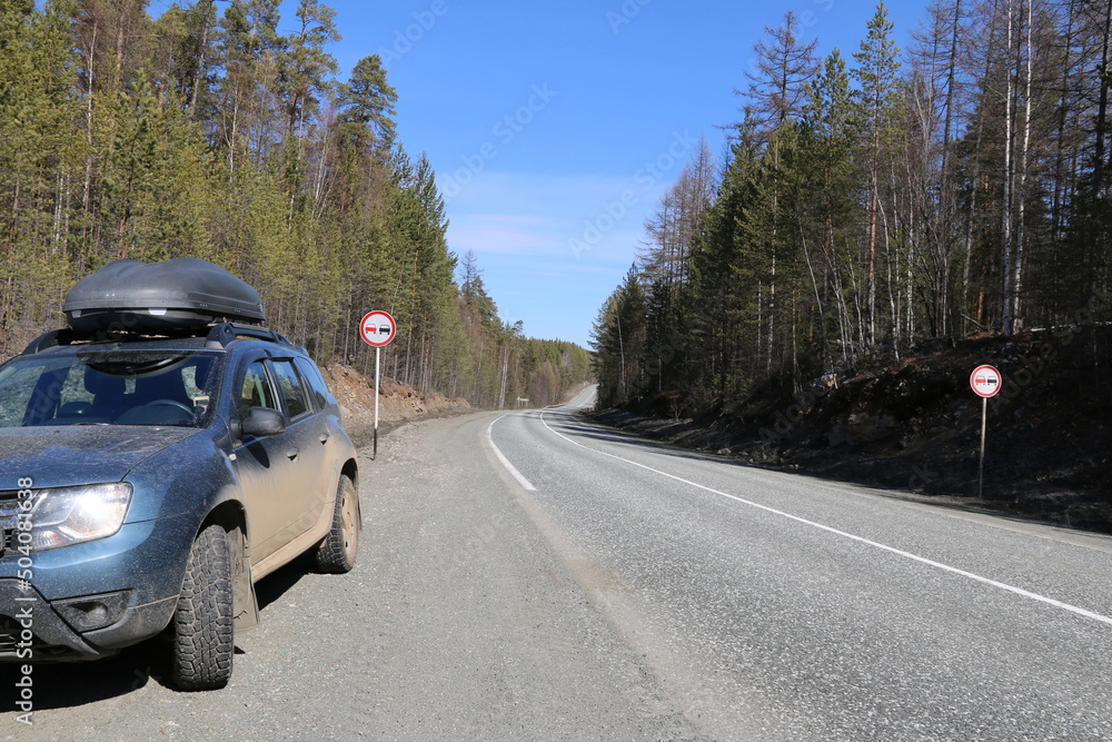 A crossover with a box on the roof on a trip around the country. Traveling by SUV around the country, car tourism. A crossover with a box on the roof on a trip around the country. Traveling by SUV around the country, car tourism.