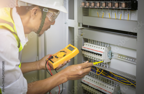 Electrical engineers test the voltage and current of the wires in the electrical cabinet control.the multimeter is in the hands of the electrician details.