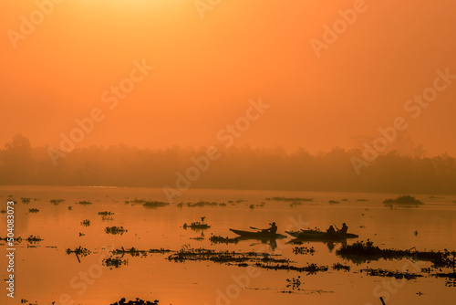 Blurred nature background of the morning sun by the sea, a beautiful golden light, among the trees, rocks and local fishing boats, the beauty of nature during the day. © bangprik