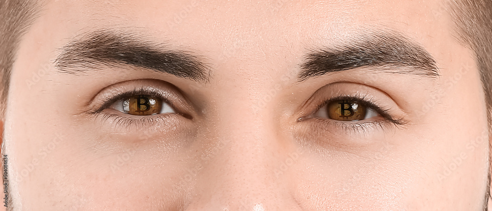 Obraz premium Handsome young man with reflection of bitcoin in his eyes, closeup