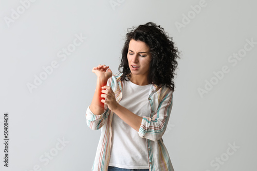 Schilderij op canvas Young woman with allergy scratching herself on grey background