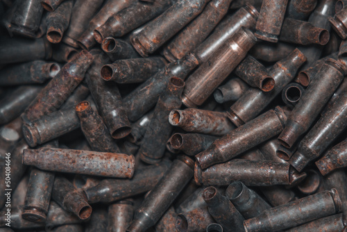  A lot of used old, rusty brass cartridge cases from the machine. Empty carbine or rifle cartridges. Background of brass ammunition cartridges to illustrate armed conflict, war or shooting.