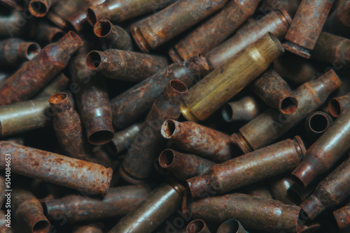  A lot of used old, rusty brass cartridge cases from the machine. Empty carbine or rifle cartridges. Background of brass ammunition cartridges to illustrate armed conflict, war or shooting.