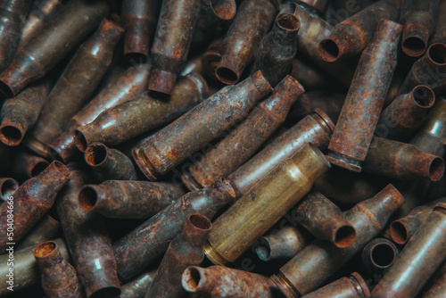  A lot of used old, rusty brass cartridge cases from the machine. Empty carbine or rifle cartridges. Background of brass ammunition cartridges to illustrate armed conflict, war or shooting.