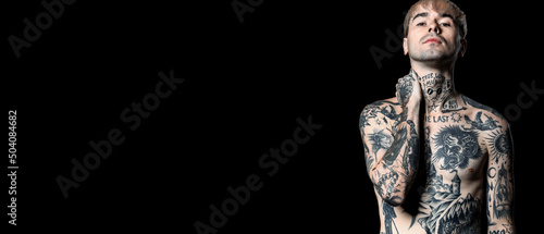 Young naked tattooed man on black background with space for text