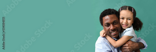 Portrait of little African-American girl hugging her father on green background with space for text