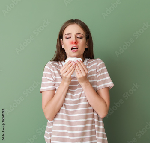 Sneezing young woman on gre...