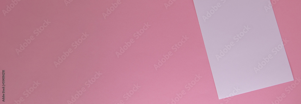 One white sheet of paper torn from a notebook, on a pink background with a copy of the space One white sheet of paper torn from a notebook, on a pink background with a copy of the space