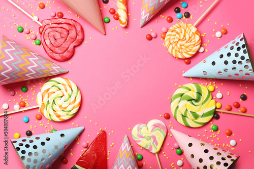 Frame made of sweet lollipops and birthday hats on color background, closeup