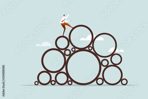 Fotografia Conceptual illustration of a businessman climbing on top of a heap of circles wi