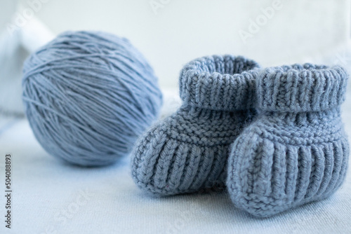Knitted socks for newborns and ball of thread. Concept of handmade knitted clothes for babies. 