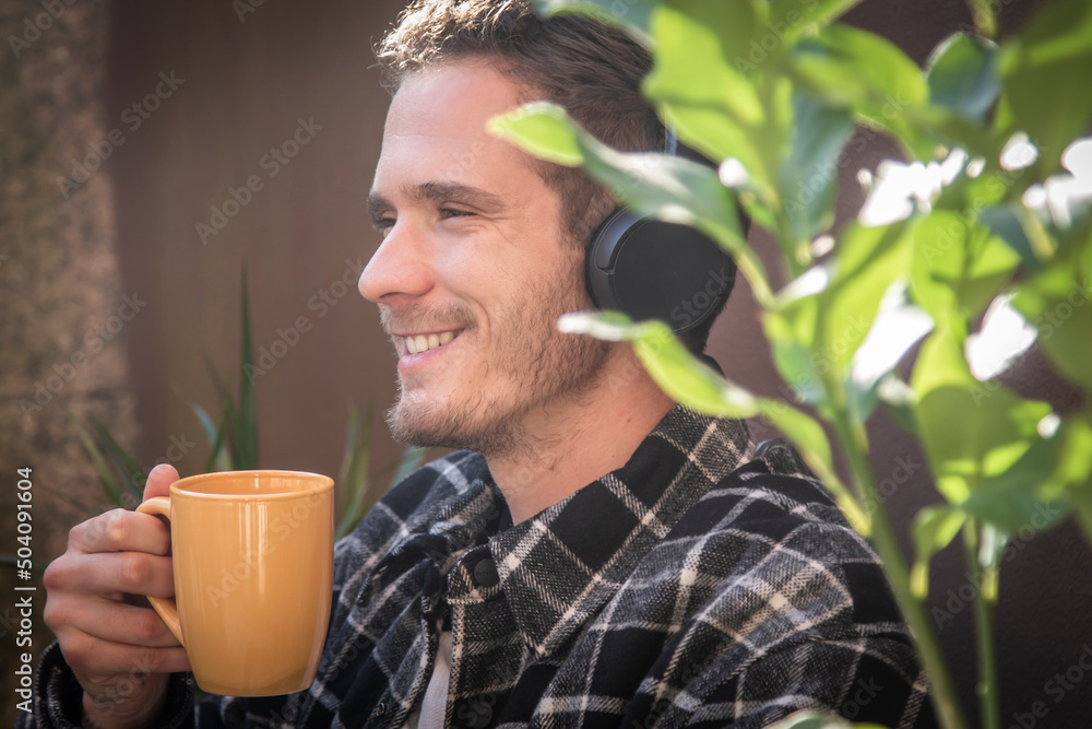 relaxed young man on terrace at home with headphones and coffee relaxed young man on terrace at home with headphones and coffee