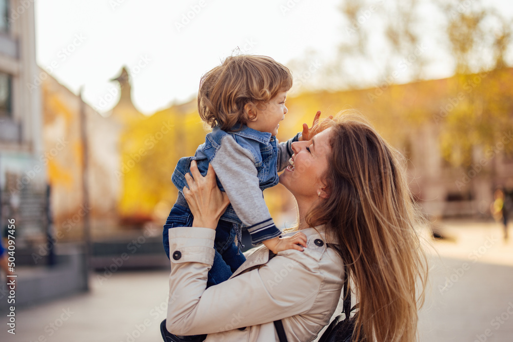 Side profile of a smiling mother and a male toddler, in mom's hands, looking happy. Side profile of a smiling mother and a male toddler, in mom's hands, looking happy.