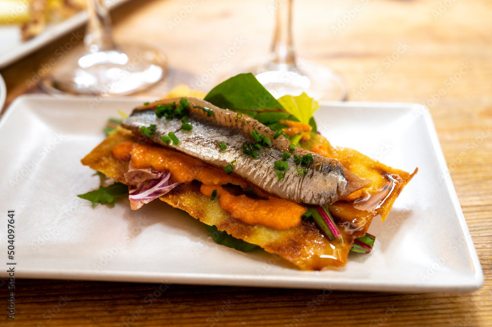 Spanish food, one tapas small piece of roasted bread cracker with vegetables puree and smoked sardine fish Spanish food, one tapas small piece of roasted bread cracker with vegetables puree and smoked sardine fish