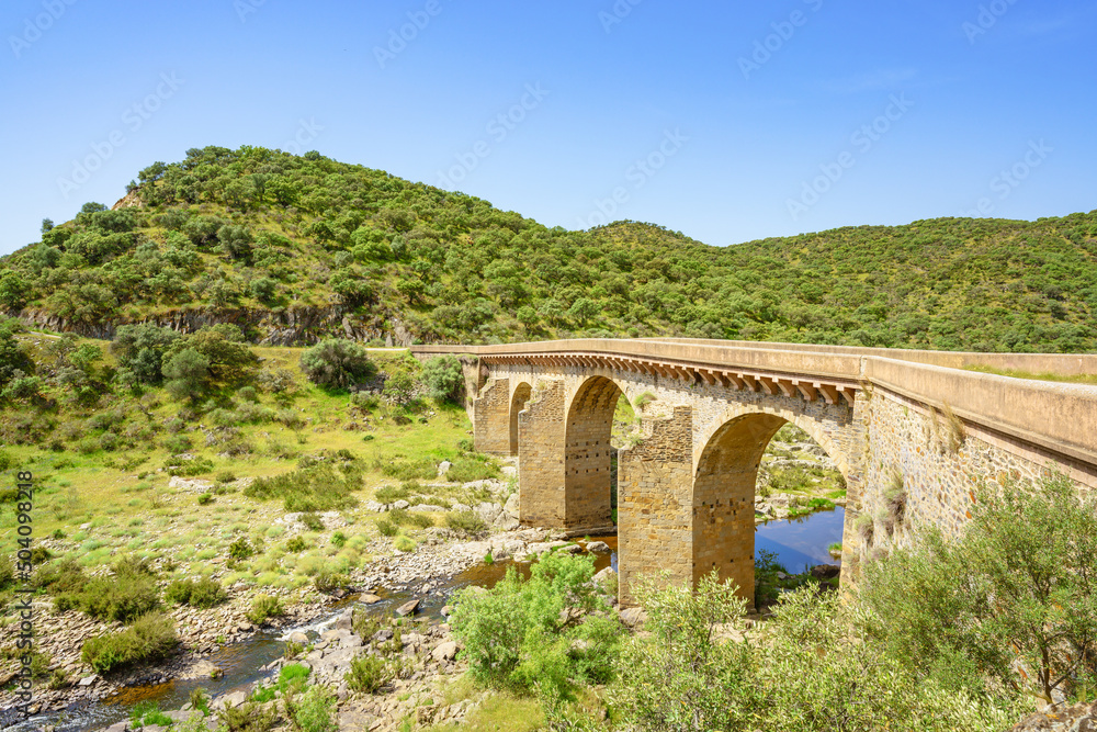 An ancient arched bridge spans over Salor river in Extremadura, Spain An ancient arched bridge spans over Salor river in Extremadura, Spain